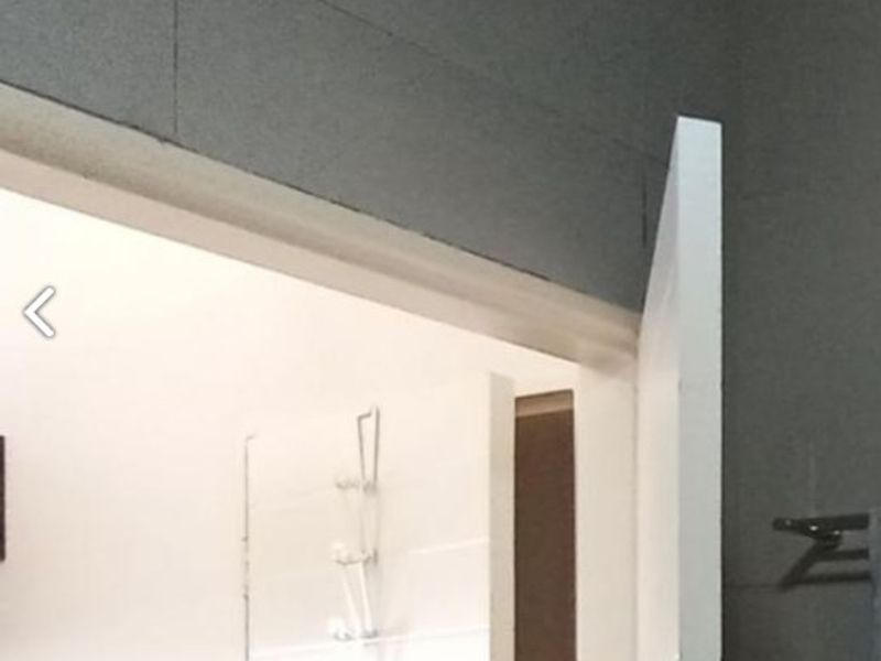 A view into a bathroom featuring tiled walls, a shower fixture, and a wall-mounted towel rail.