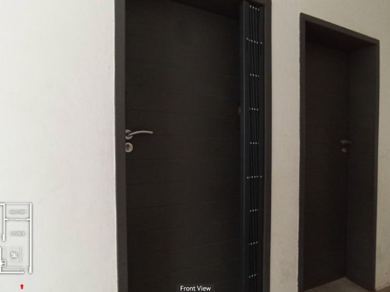 A hallway interior featuring dark-toned internal doors and a security gate, with a floor plan overlay visible in the corner.