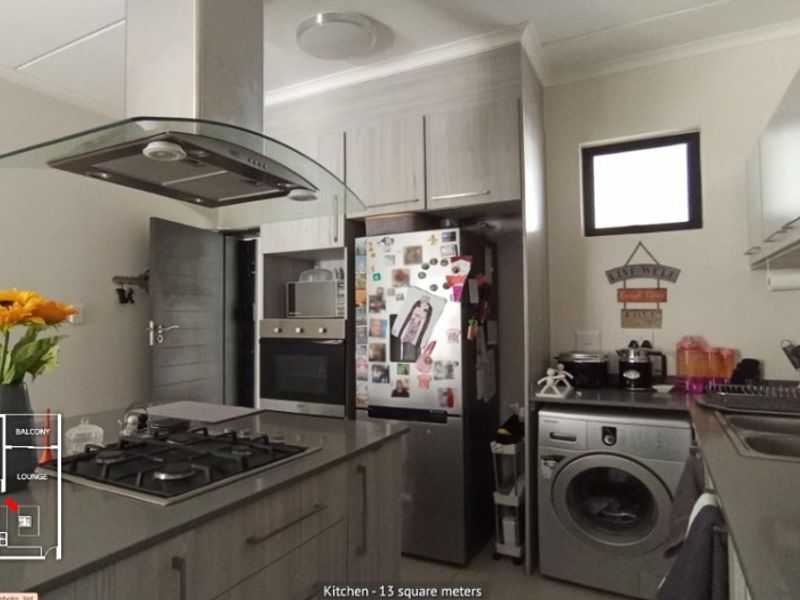 Modern kitchen featuring stone countertops, gas hob, extractor fan, built-in oven, and ample cabinetry with an integrated laundry area.