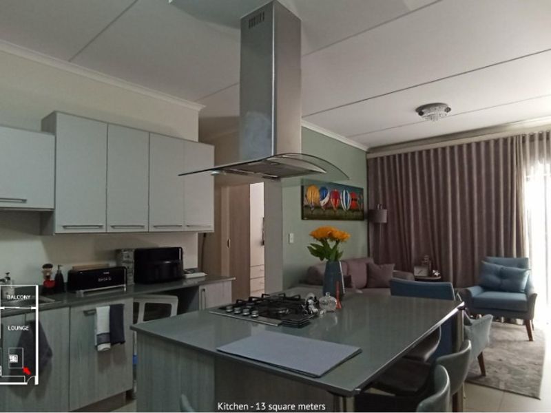 Open-plan kitchen and living area featuring a central island with a gas hob, extractor fan, and modern cabinetry.