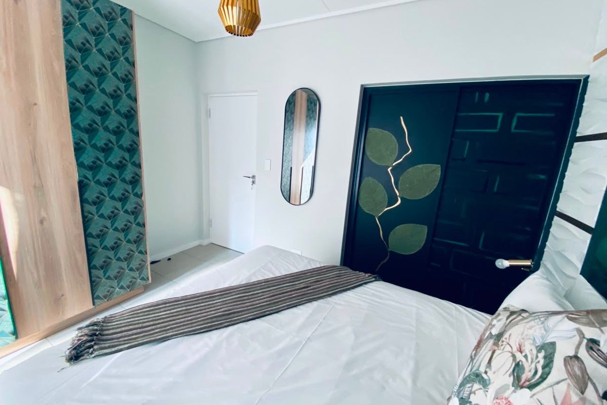 A well-maintained bedroom featuring a built-in wardrobe with decorative paneling and a modern pendant light fixture.