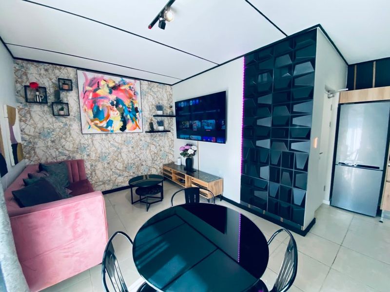 Modern open-plan living area featuring contemporary track lighting, decorative wall finishes, and a unique geometric feature wall partition.