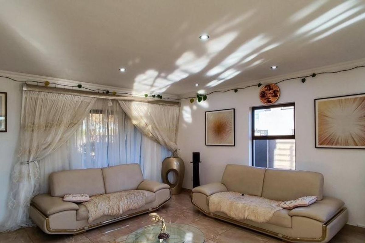 A well-lit living room featuring tiled flooring, recessed downlighting, and coving, providing a comfortable and functional space for relaxation.