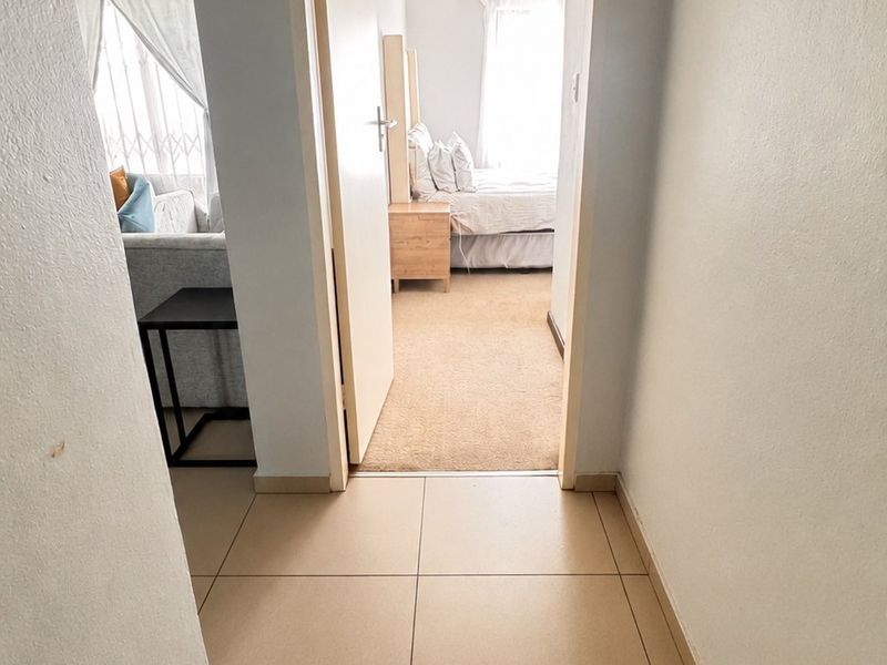 A clean, tiled hallway providing access to adjacent living and bedroom areas within the apartment.