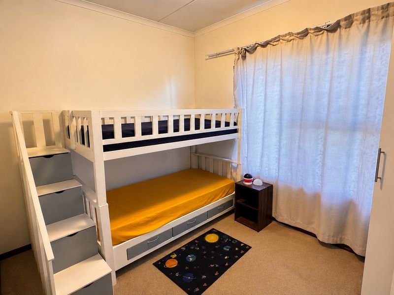 A functional bedroom featuring neutral walls, carpeted flooring, and a built-in wardrobe for storage.