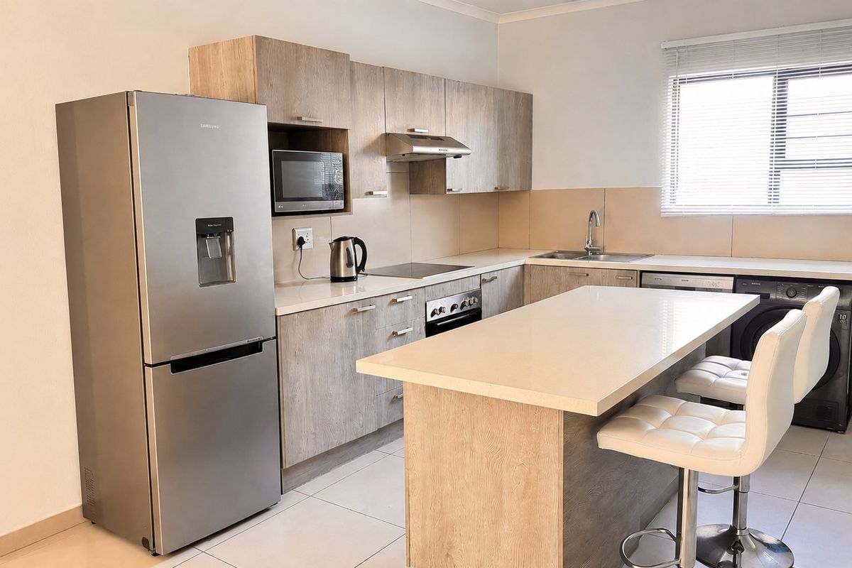 Modern kitchen featuring light wood-finish cabinetry, stone countertops, a central island, and integrated appliances, offering a clean and functional culinary space.