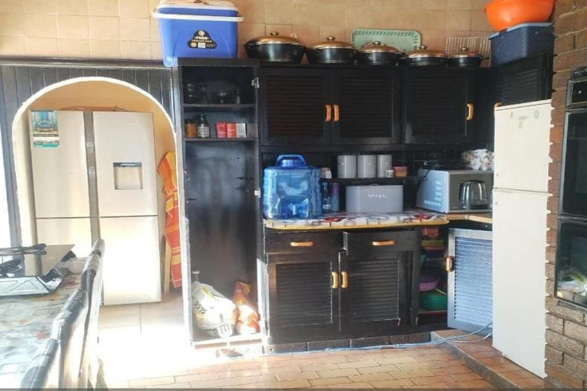 A dated kitchen featuring dark built-in cabinetry, a brick wall element, and tiled finishes, offering potential for a modern renovation.