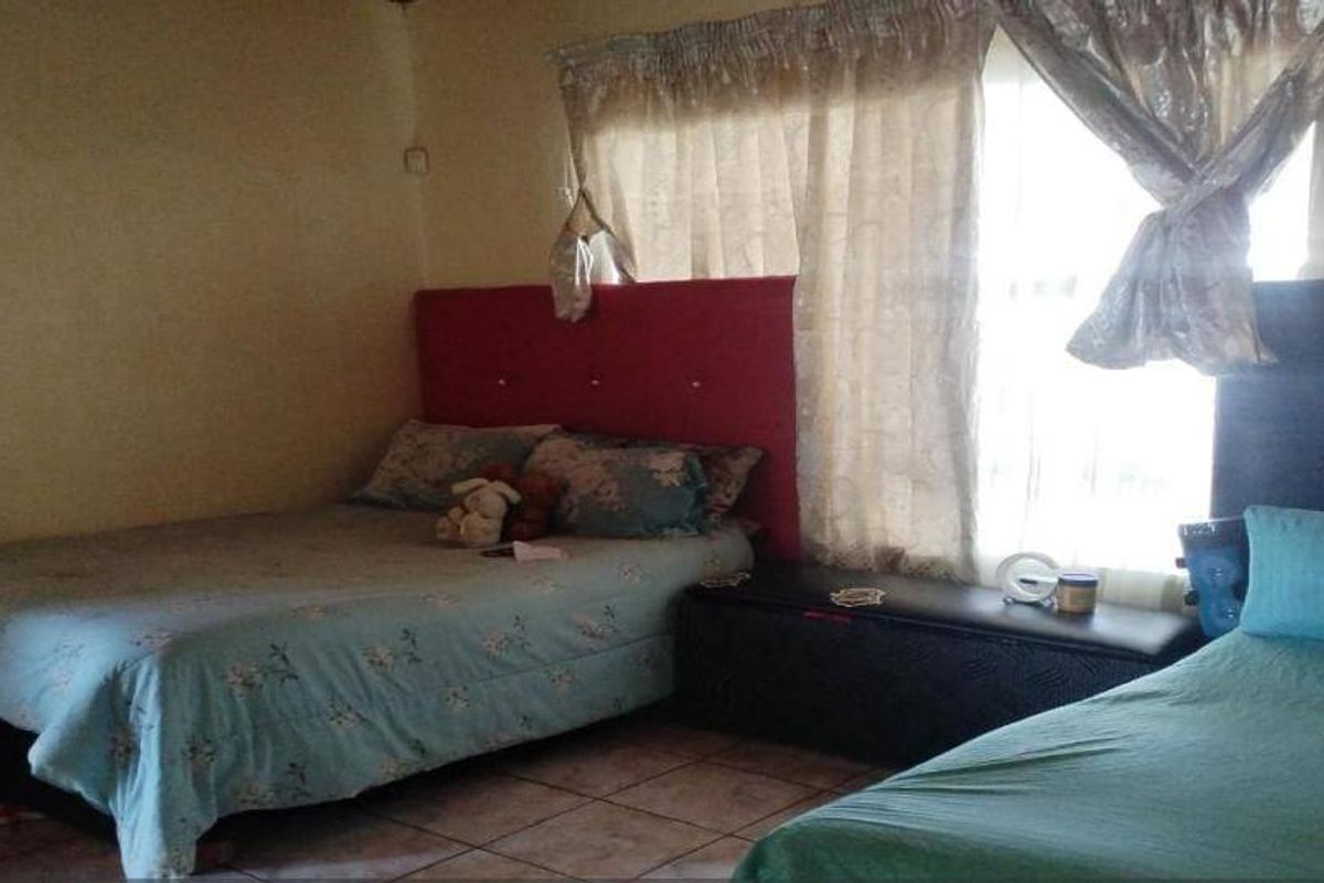 A bedroom featuring tiled flooring and window treatments, providing a functional space for rest.
