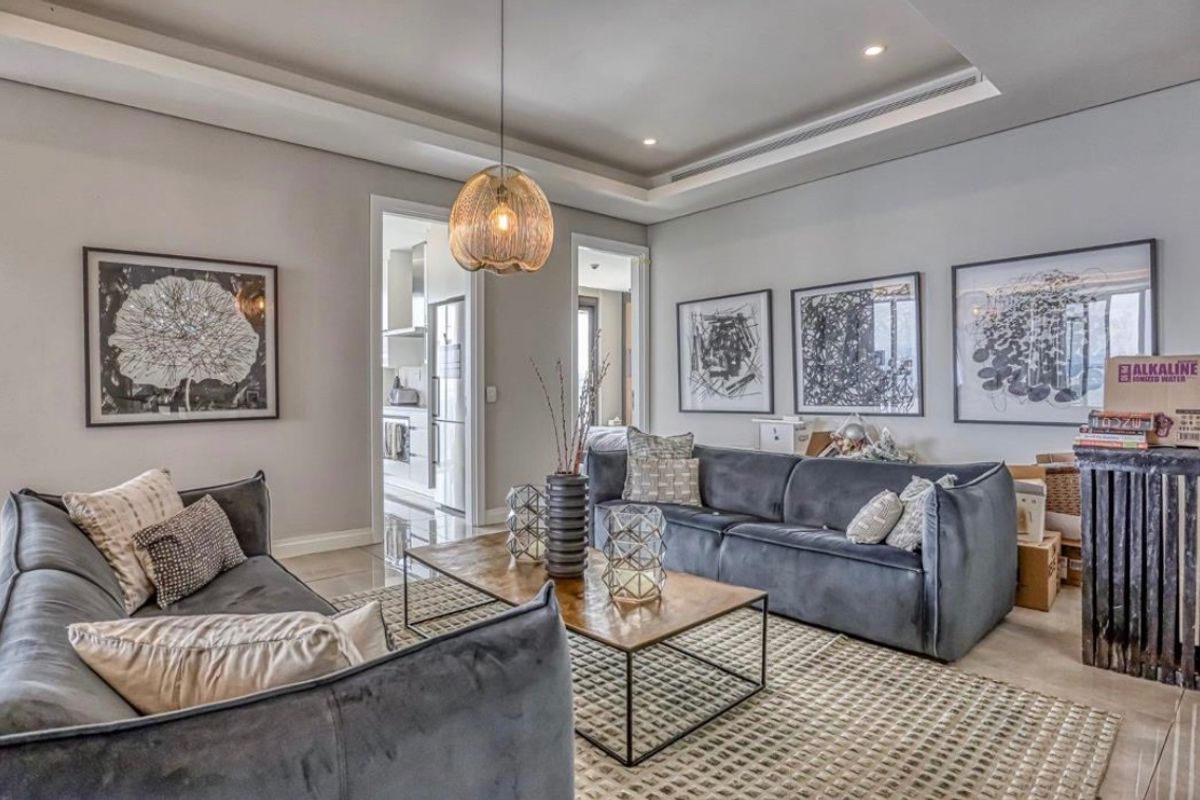 A well-maintained living room featuring recessed ceiling details, modern downlighting, and polished tile flooring, providing a bright and contemporary living space.