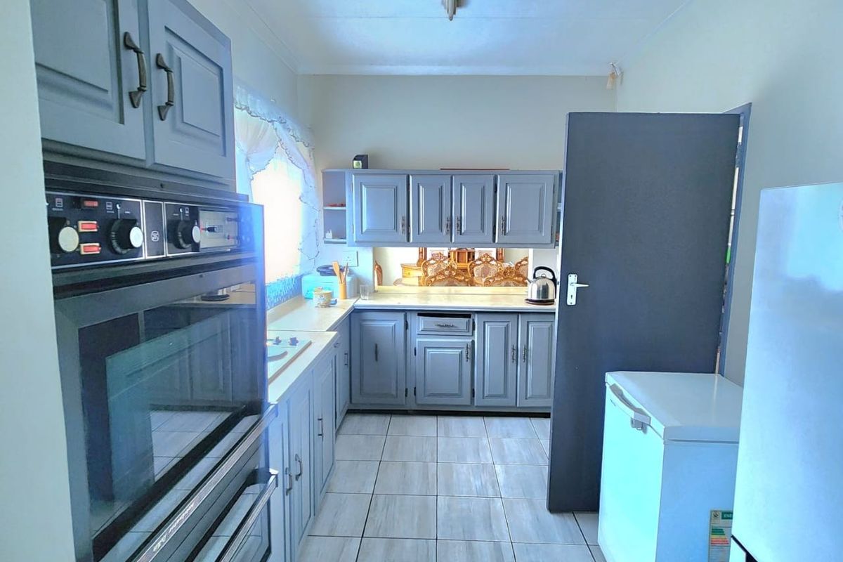 A functional kitchen featuring grey built-in cabinetry, a double oven, laminate countertops, and light-colored tiled flooring.