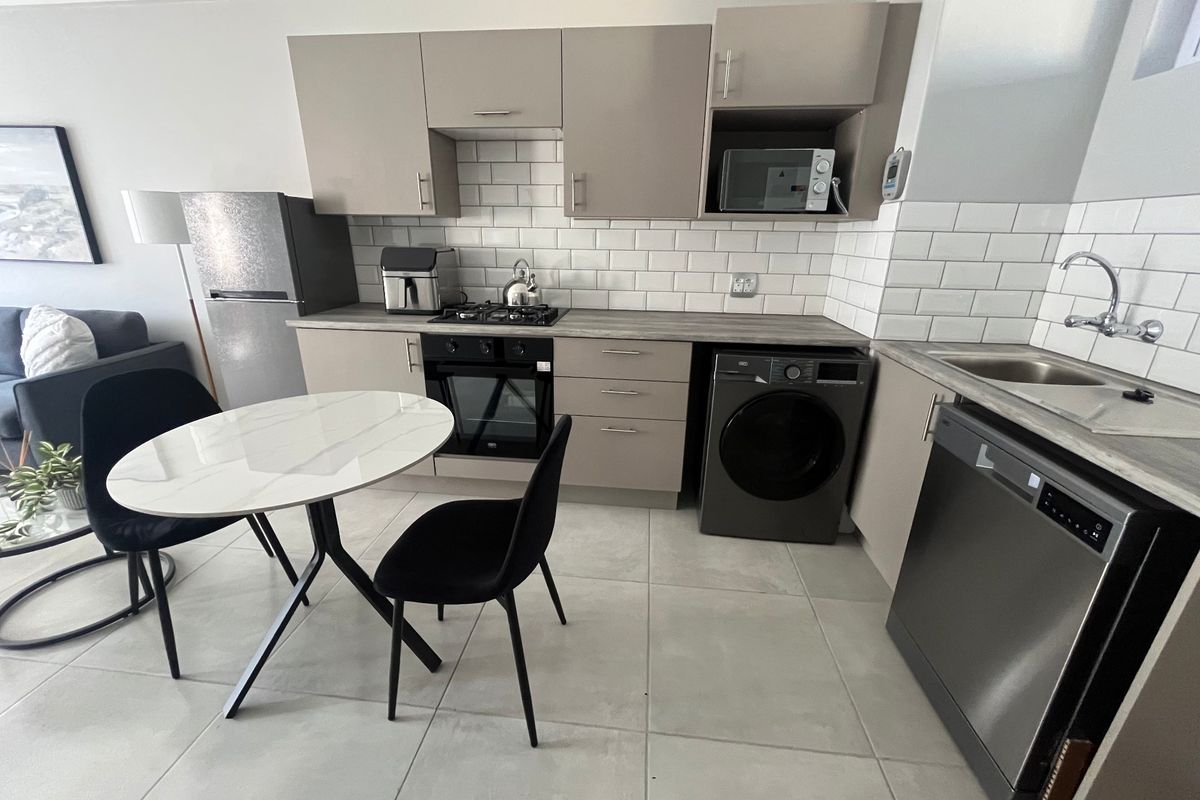 Modern kitchen featuring neutral cabinetry, subway tile backsplash, gas hob, built-in oven, and integrated space for appliances with durable tiled flooring.