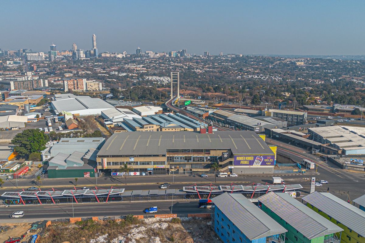 Aerial view of a large industrial warehouse facility situated in a commercial district with prominent street frontage and proximity to major transport infrastructure.