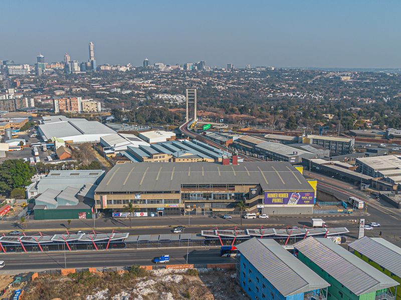 Aerial view of a large industrial warehouse facility situated in a commercial district with prominent street frontage and proximity to major transport infrastructure.