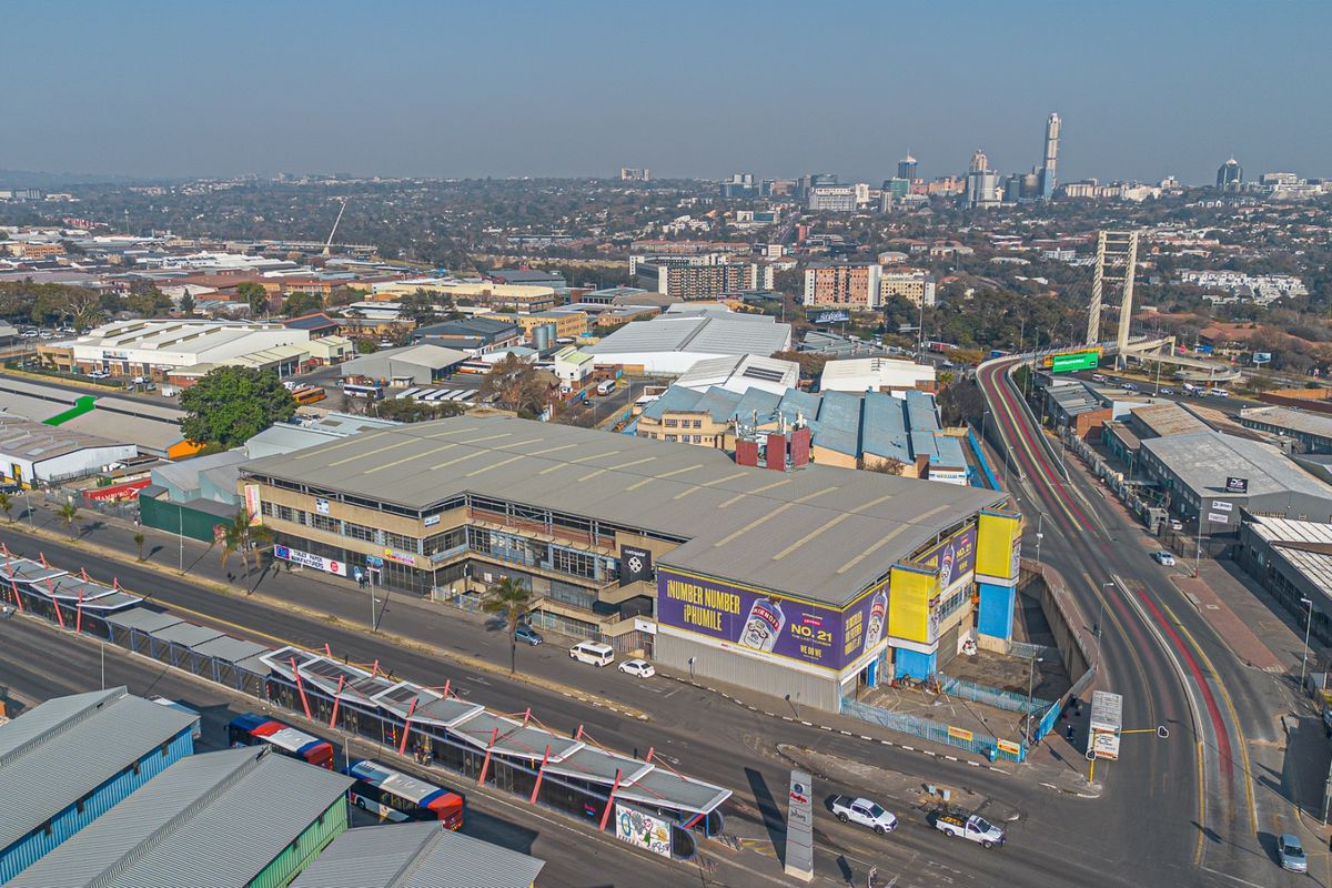 Aerial view of a large industrial warehouse facility situated in a commercial district, featuring prominent street frontage and proximity to major transport infrastructure.