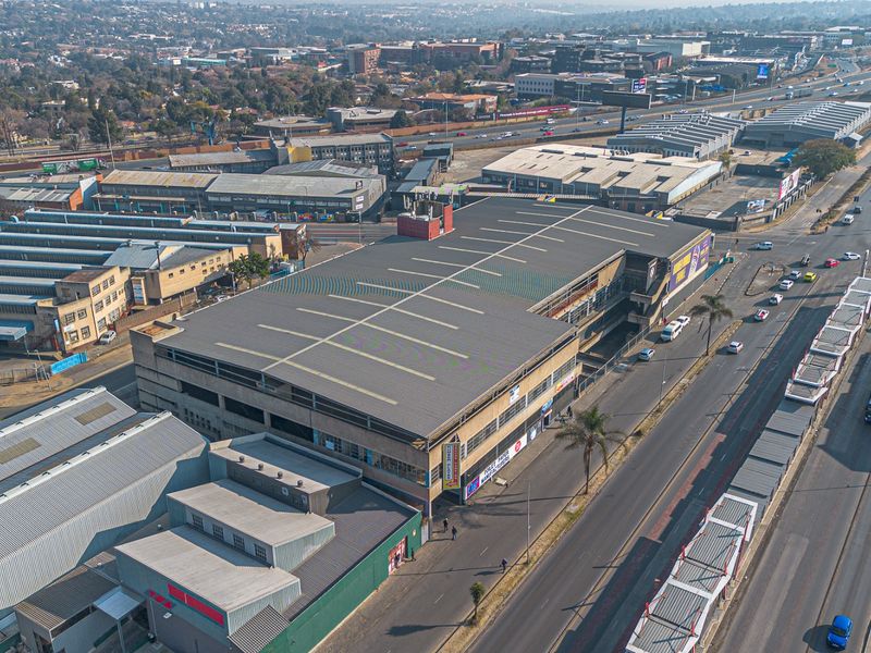 Aerial view of a multi-level industrial and commercial building situated in a busy urban industrial zone with adjacent road access.