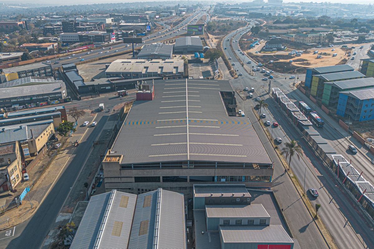 Aerial view of a large industrial warehouse facility situated in a busy urban commercial and transport hub.