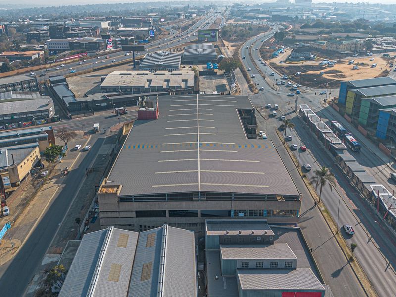 Aerial view of a large industrial warehouse facility situated in a busy urban commercial and transport hub.