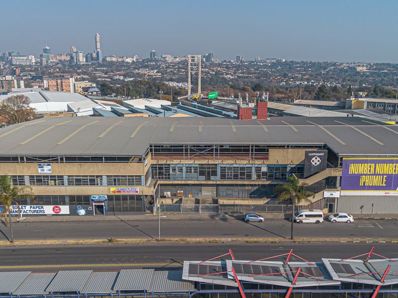 Aerial view of a multi-level industrial building featuring a corrugated metal roof, large advertising signage, and street-level access.