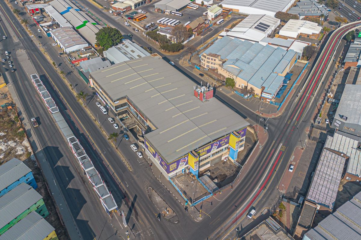 Aerial view of a multi-level industrial property situated on a prominent corner lot with surrounding road access and parking facilities.