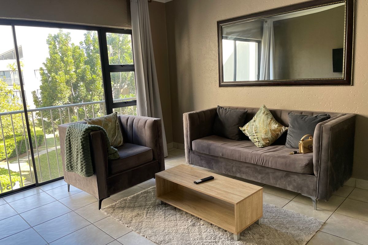 A living room featuring tiled flooring and a large sliding glass door providing natural light and access to an outdoor balcony area.
