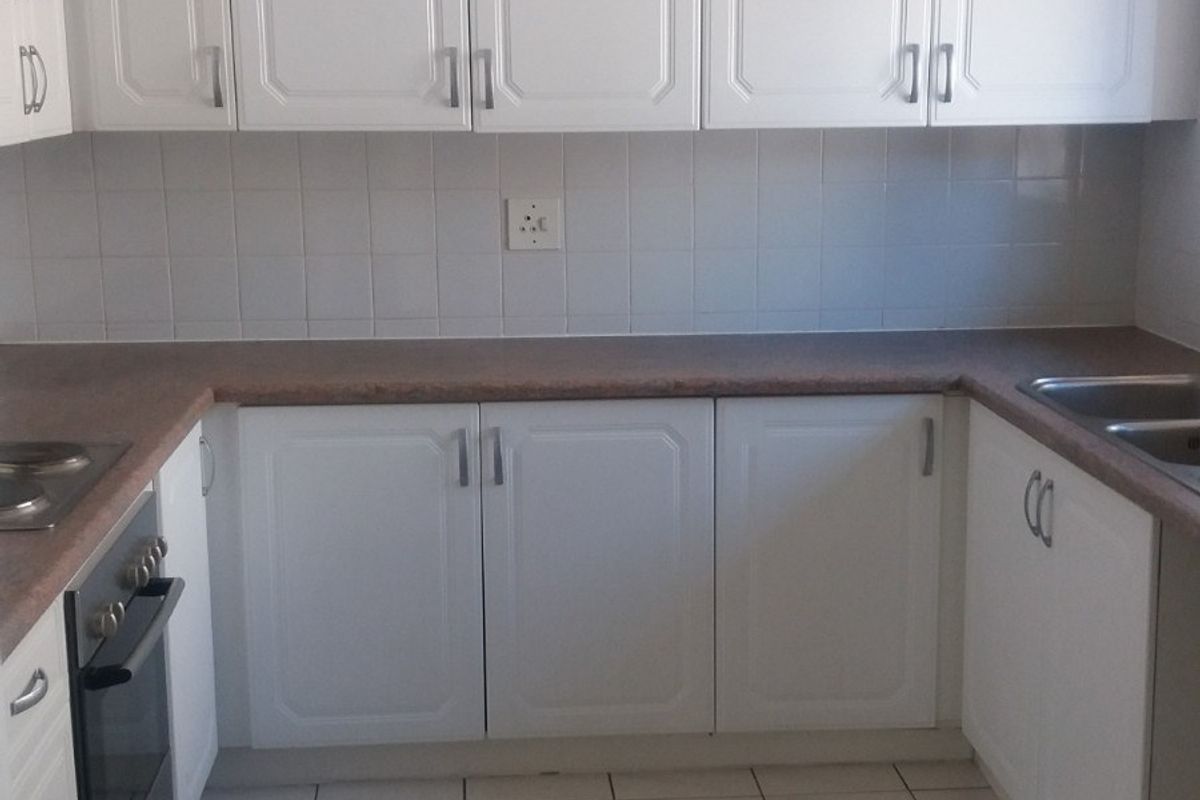 A functional kitchen featuring white cabinetry, laminate countertops, tiled backsplash, built-in oven, and a double sink with tiled flooring.