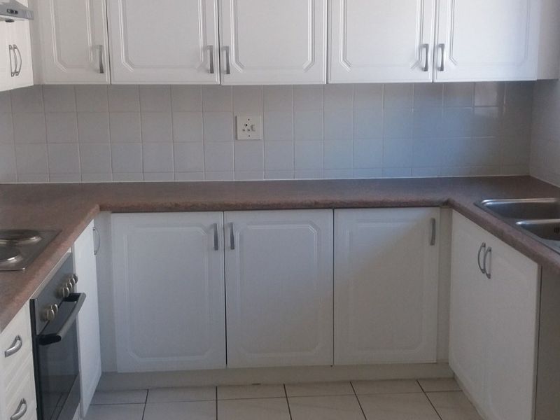 A functional kitchen featuring white cabinetry, laminate countertops, tiled backsplash, built-in oven, and a double sink with tiled flooring.