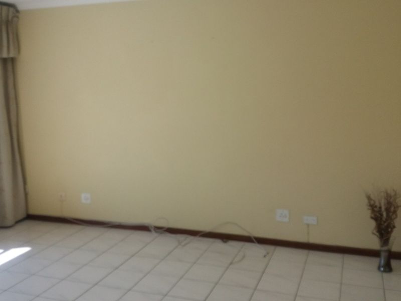 An empty living room featuring neutral tiled flooring and curtain rails, providing a blank canvas for interior design.