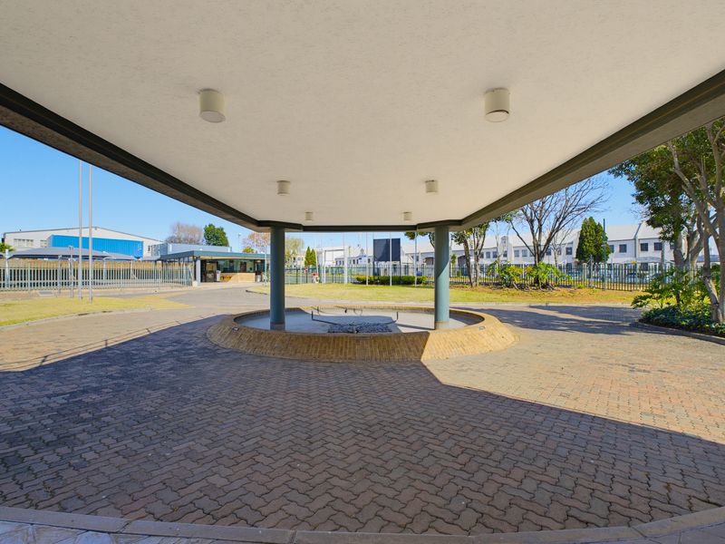 A spacious commercial porte-cochere entrance featuring a paved driveway, central circular feature, and covered overhead structure with integrated lighting.