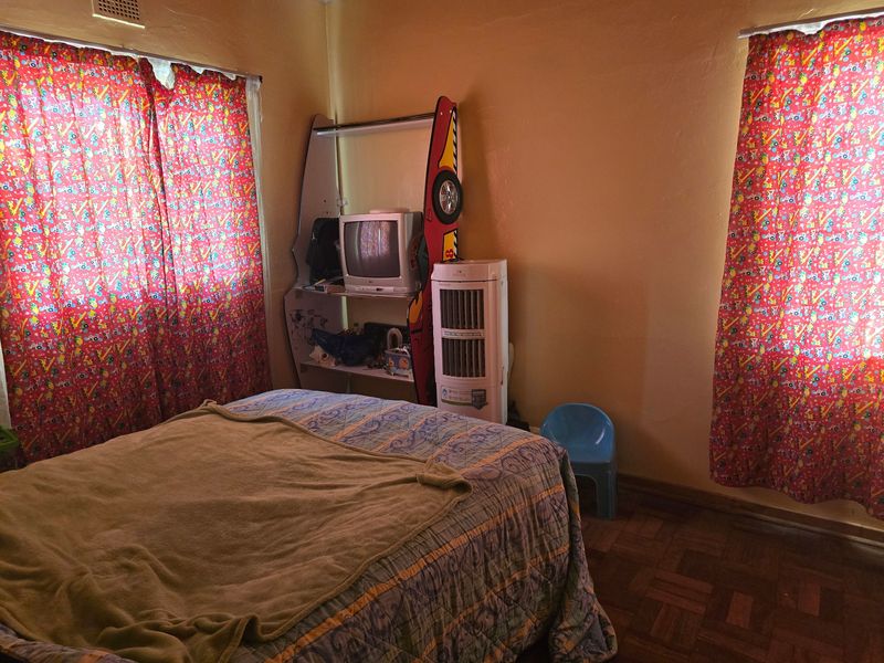 A bedroom featuring classic parquet flooring and dual windows, offering a functional space ready for cosmetic updates and modern interior styling.
