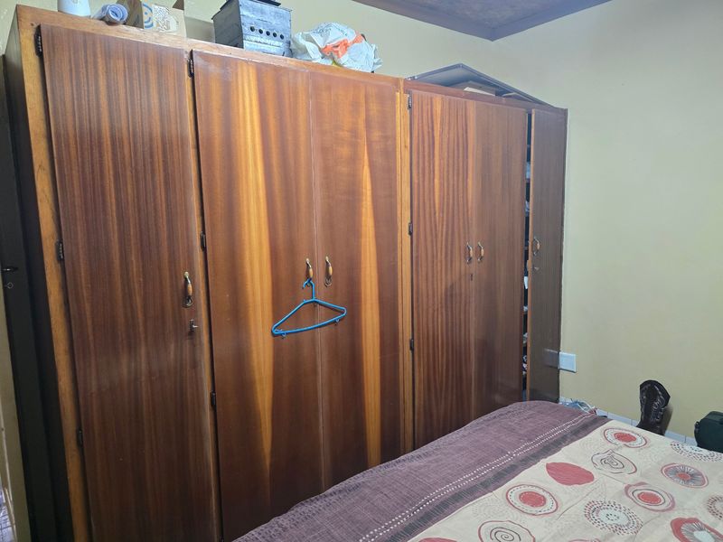 A bedroom featuring a large, full-height built-in wooden wardrobe with multiple doors.