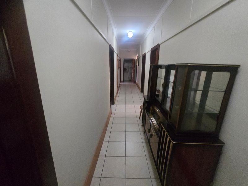 A long, tiled hallway providing access to multiple rooms, featuring neutral walls and traditional coving.
