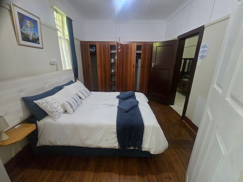 A well-maintained bedroom featuring polished timber flooring, built-in wooden wardrobes, and classic architectural details like a picture rail.