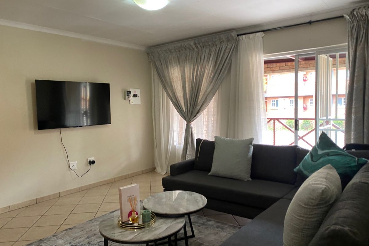 A comfortable living room featuring tiled flooring, a ceiling light fixture, and a sliding glass door providing access to the outdoor area.