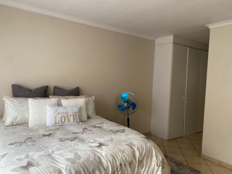 A bedroom featuring neutral wall tones, tiled flooring, and built-in storage cupboards.