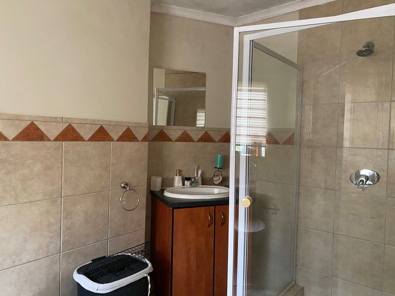 A functional bathroom featuring a vanity cabinet with a drop-in basin and a separate shower enclosure with tiled wall finishes.