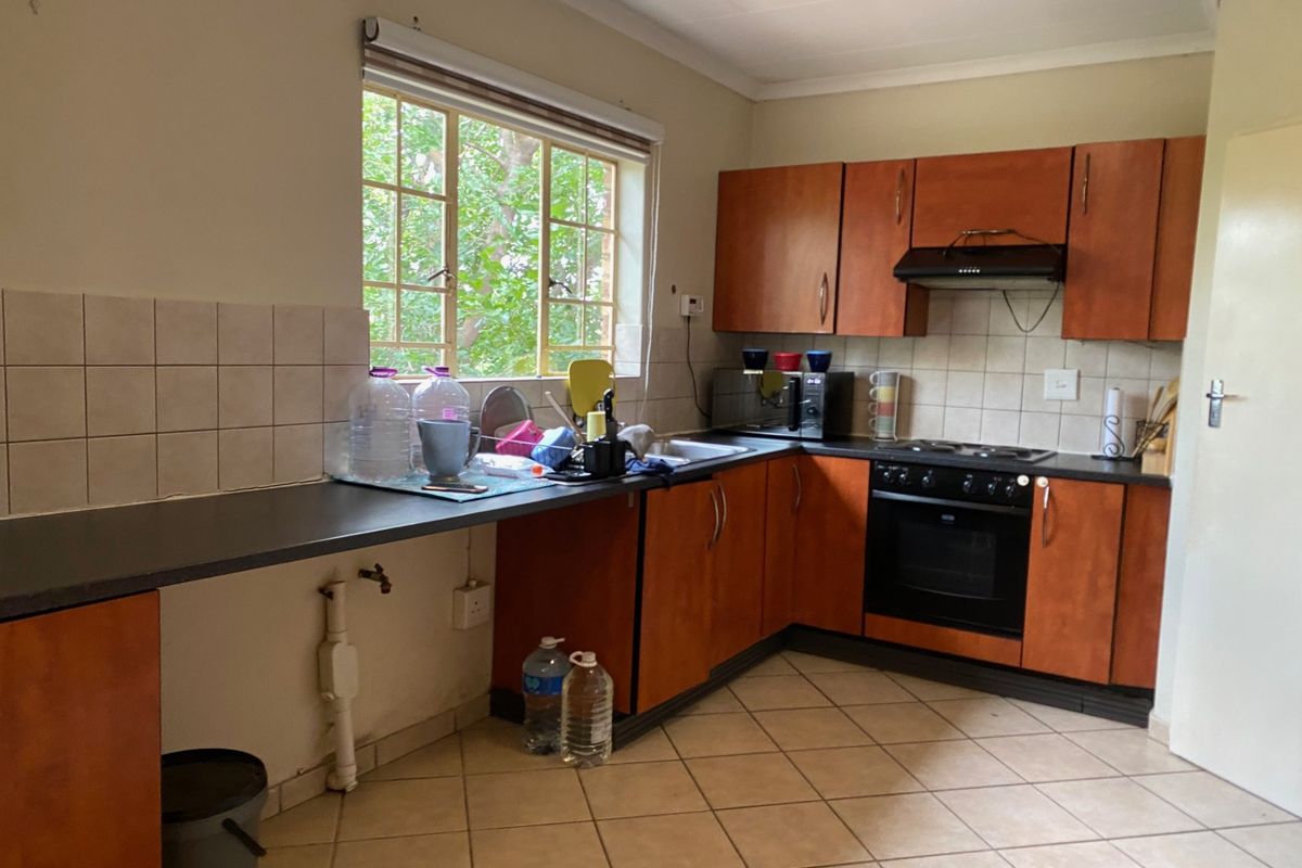 A functional kitchen featuring wooden cabinetry, built-in oven with hob, extractor fan, and tiled flooring, offering a practical layout for daily use.