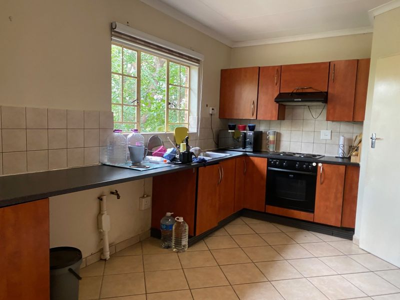 A functional kitchen featuring wooden cabinetry, built-in oven with hob, extractor fan, and tiled flooring, offering a practical layout for daily use.