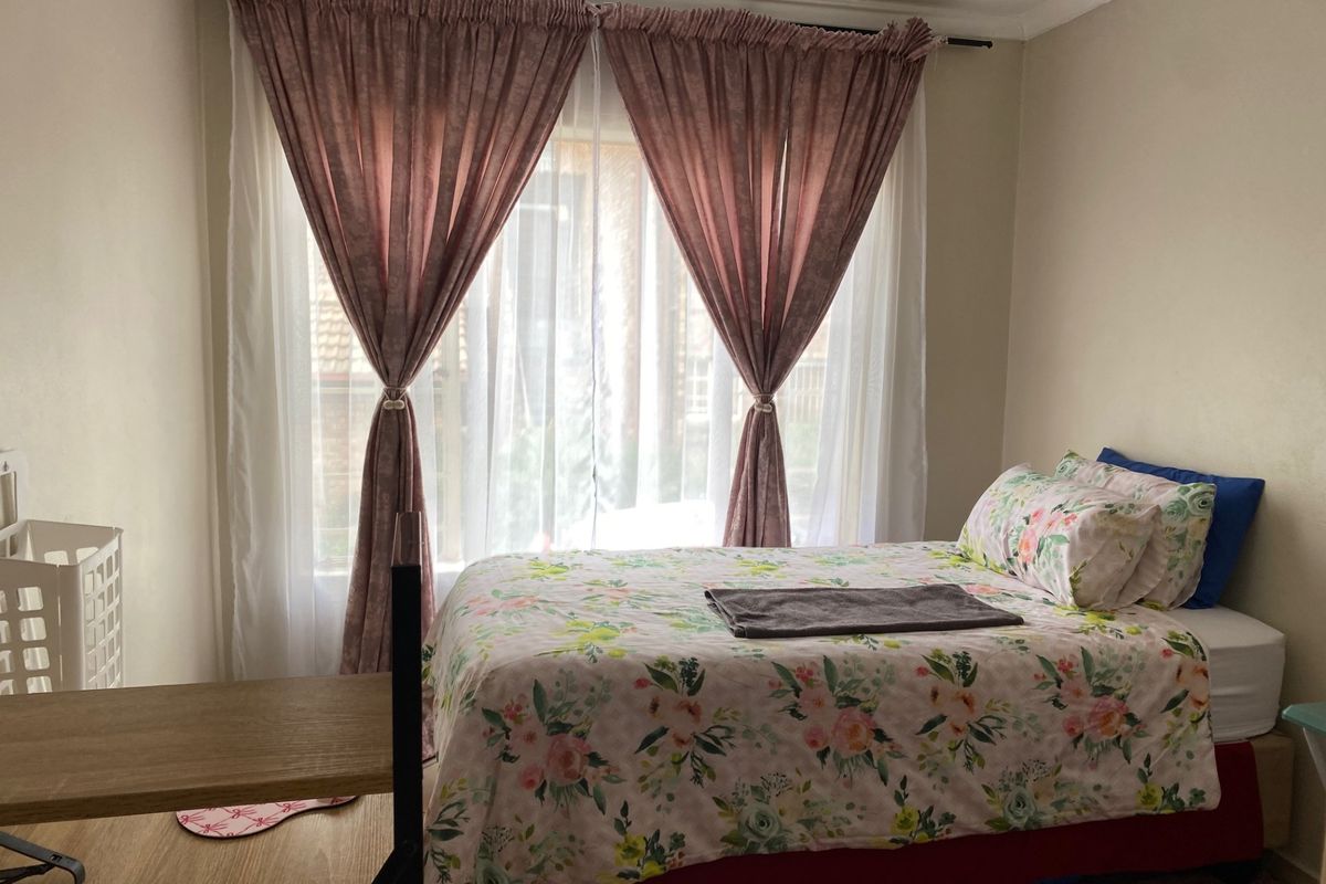 A functional bedroom featuring laminate flooring and coving, with natural light provided by a large window.