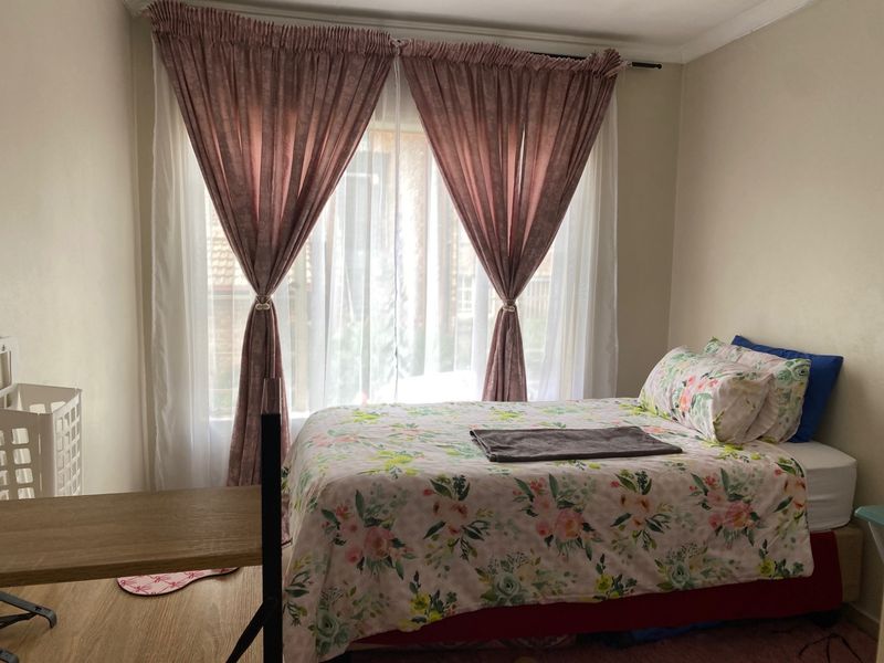 A functional bedroom featuring laminate flooring and coving, with natural light provided by a large window.