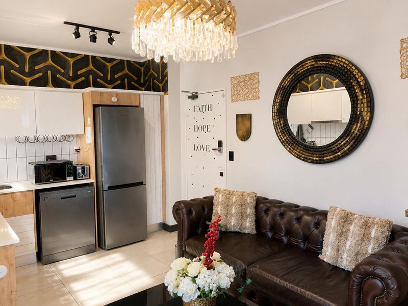 Open plan living area featuring a compact kitchen with modern cabinetry, tiled flooring, and integrated appliance space, seamlessly connected to the lounge area.