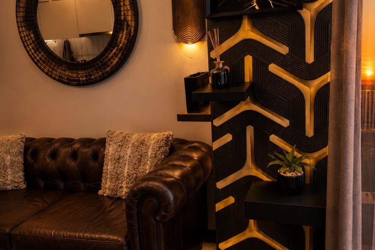A stylishly appointed living area featuring custom geometric wall paneling, warm accent lighting, and a sophisticated modern aesthetic.
