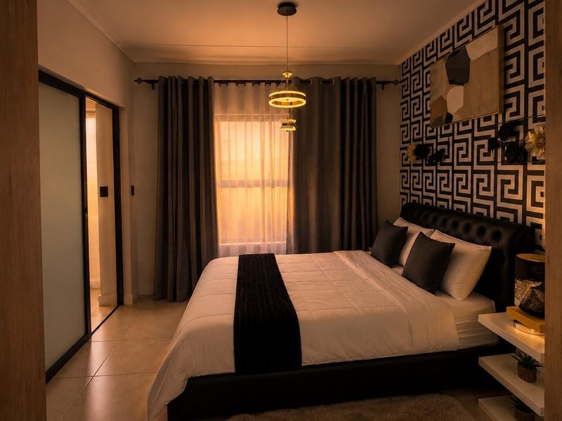 A well-appointed bedroom featuring tiled flooring, a modern pendant light fixture, and a sliding door leading to an adjacent space.