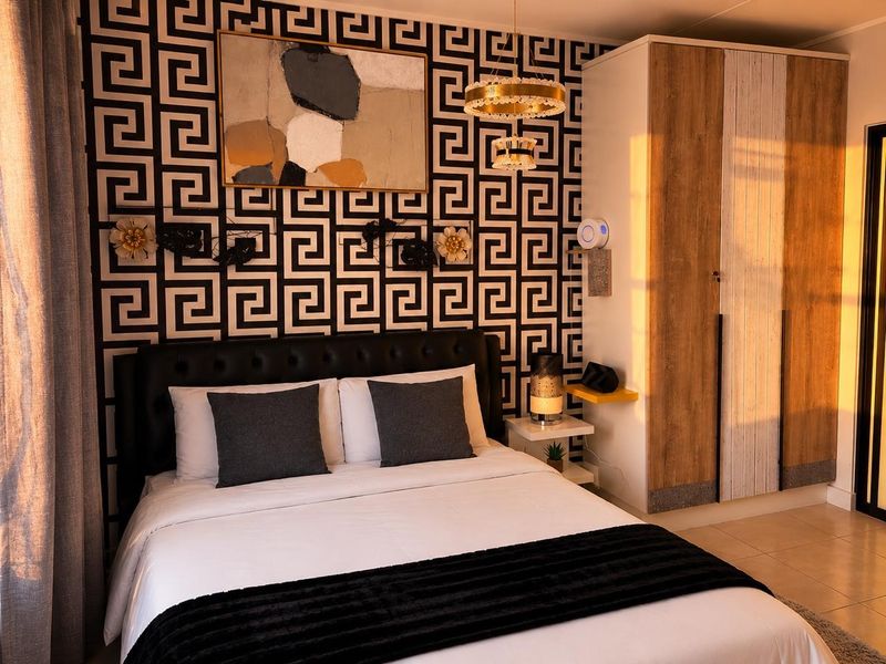 A well-lit bedroom featuring a built-in wardrobe, tiled flooring, and a decorative feature wall with a modern pendant light fixture.