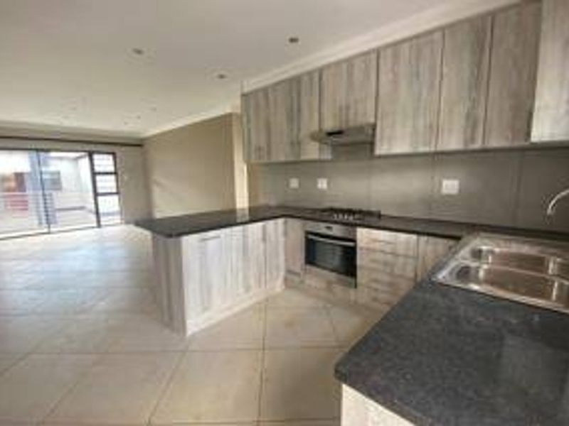 Open-plan kitchen and living area featuring modern cabinetry, granite countertops, built-in appliances, and large sliding doors leading to an outdoor space.