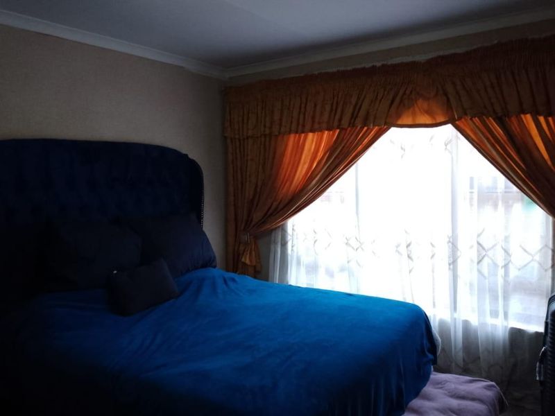 A bedroom featuring a large window with draped curtains, providing natural light to the space.