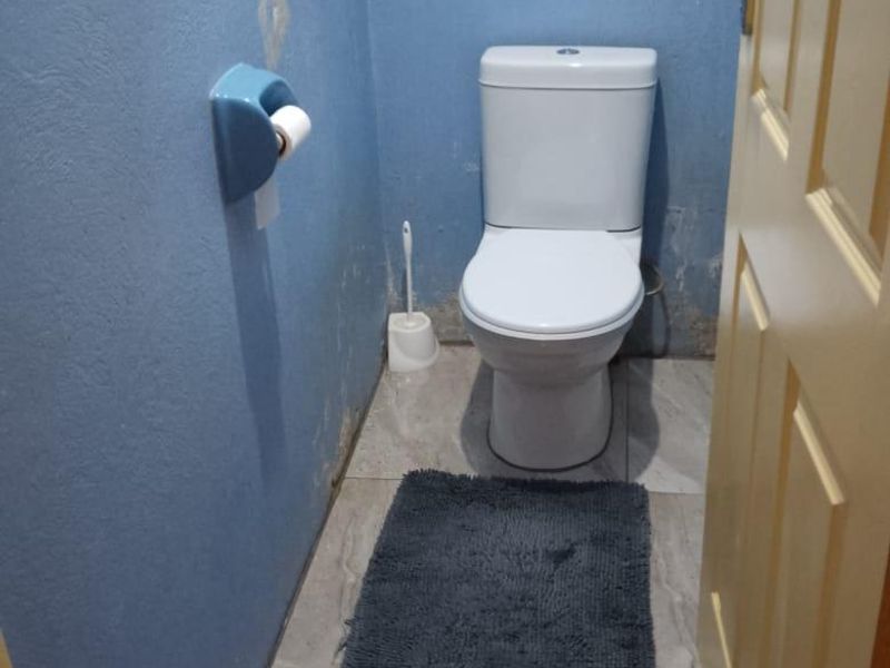 A small bathroom featuring a white toilet and tiled flooring, currently requiring wall repairs and repainting to improve the overall condition.