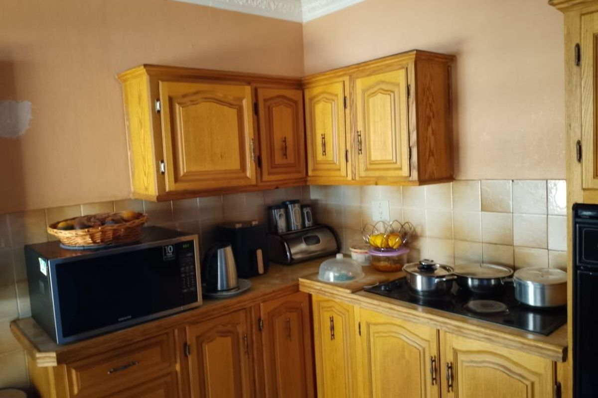 A dated kitchen featuring traditional wooden cabinetry, a ceramic tile backsplash, and built-in cooking appliances, offering potential for a modern renovation.