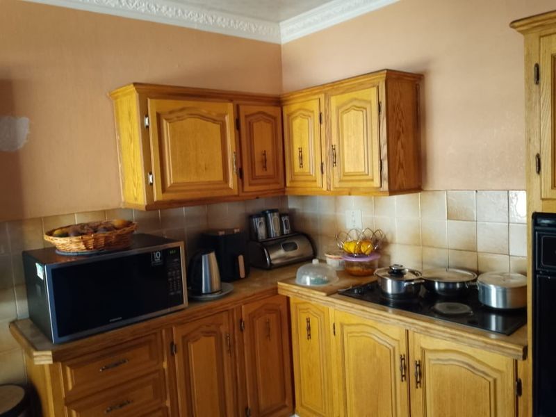 A dated kitchen featuring traditional wooden cabinetry, a ceramic tile backsplash, and built-in cooking appliances, offering potential for a modern renovation.