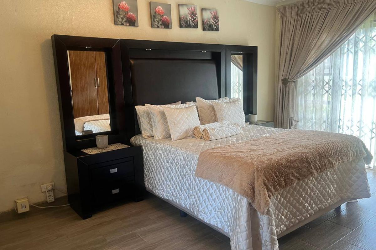A well-lit bedroom featuring tiled flooring and a sliding glass door with an integrated security gate, providing access to the exterior.