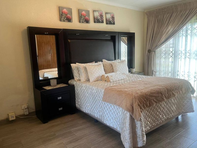 A well-lit bedroom featuring tiled flooring and a sliding glass door with an integrated security gate, providing access to the exterior.